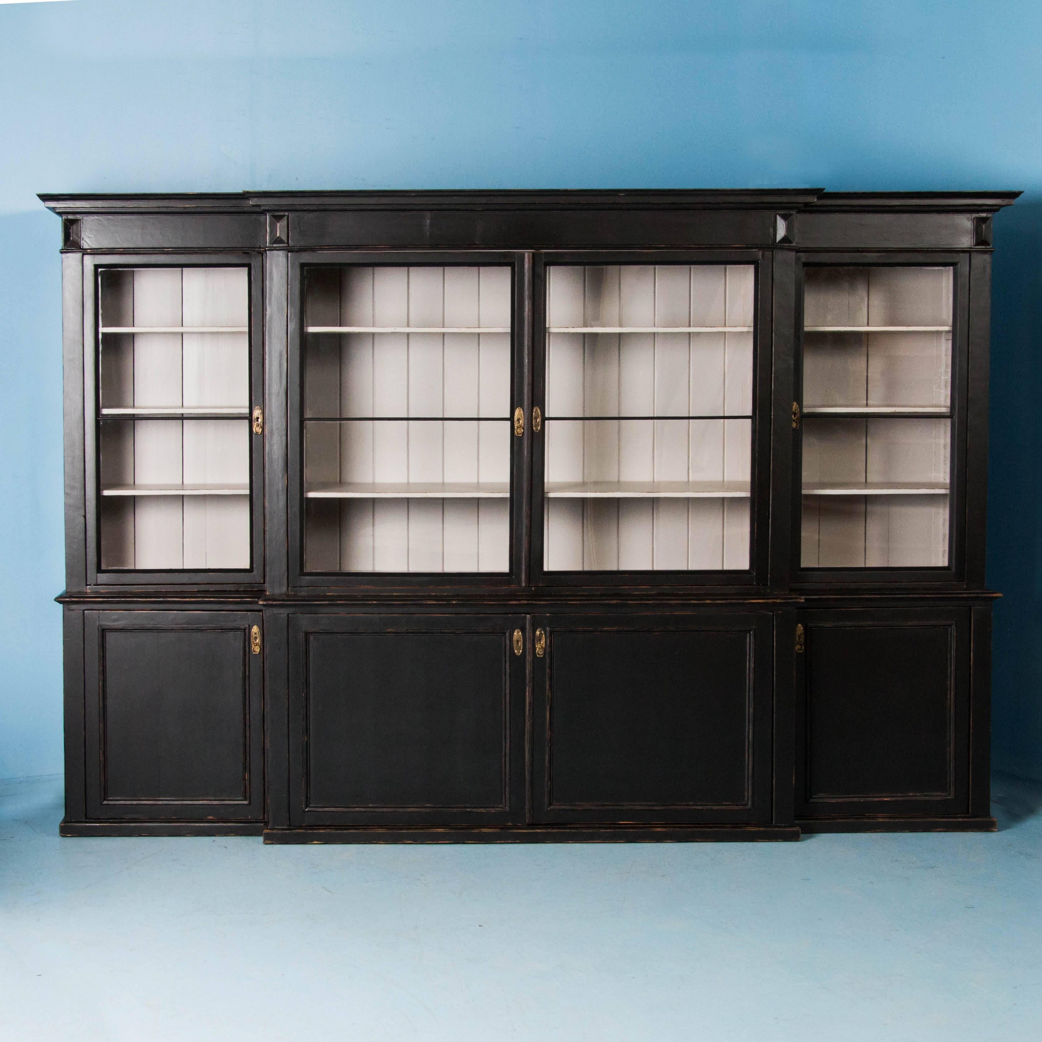 This remarkable breakfront bookcase originally served as a large display cabinet for a grocer or other shop owner in the 1800's of Denmark. It was likely placed against a long wall, with the store counter in front of it. Today, it has been given a
