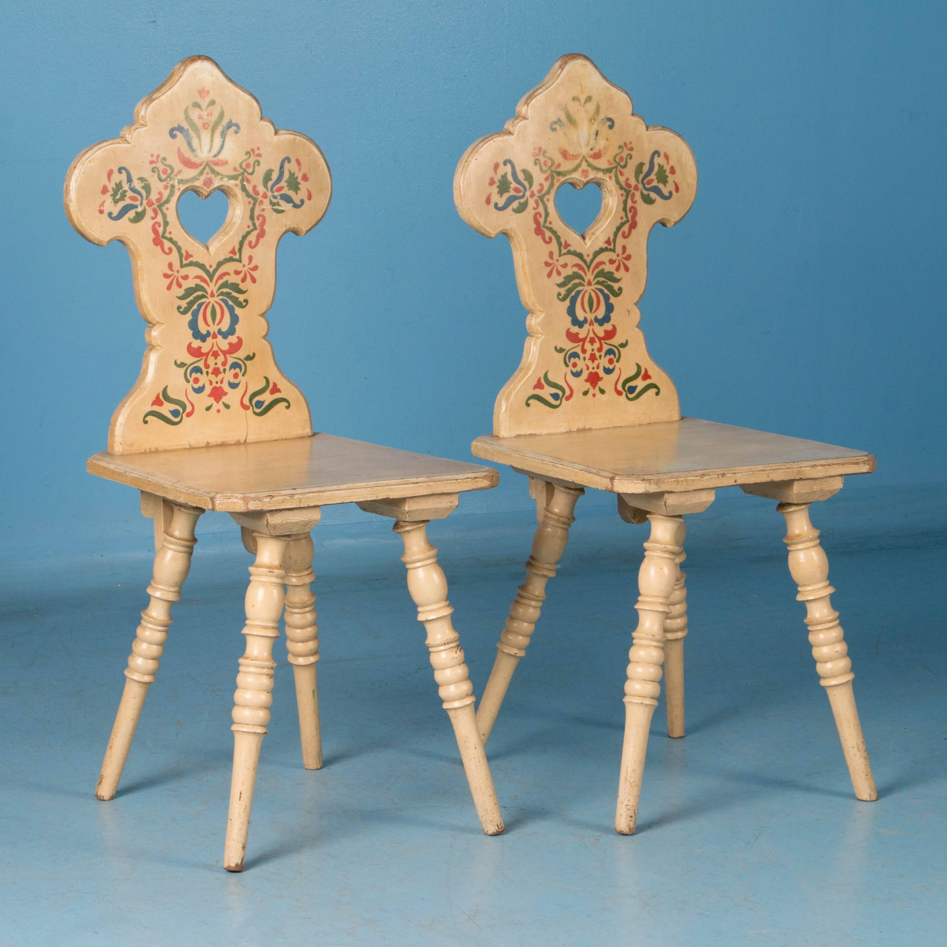 This delightful pair of chairs have a traditional heart shaped cut-out in the back, which brings to mind a quaint Tyrolean cabin in the Austrian hills. The soft yellow is accented by red, blue and green folk art stencil/painted flowers and
