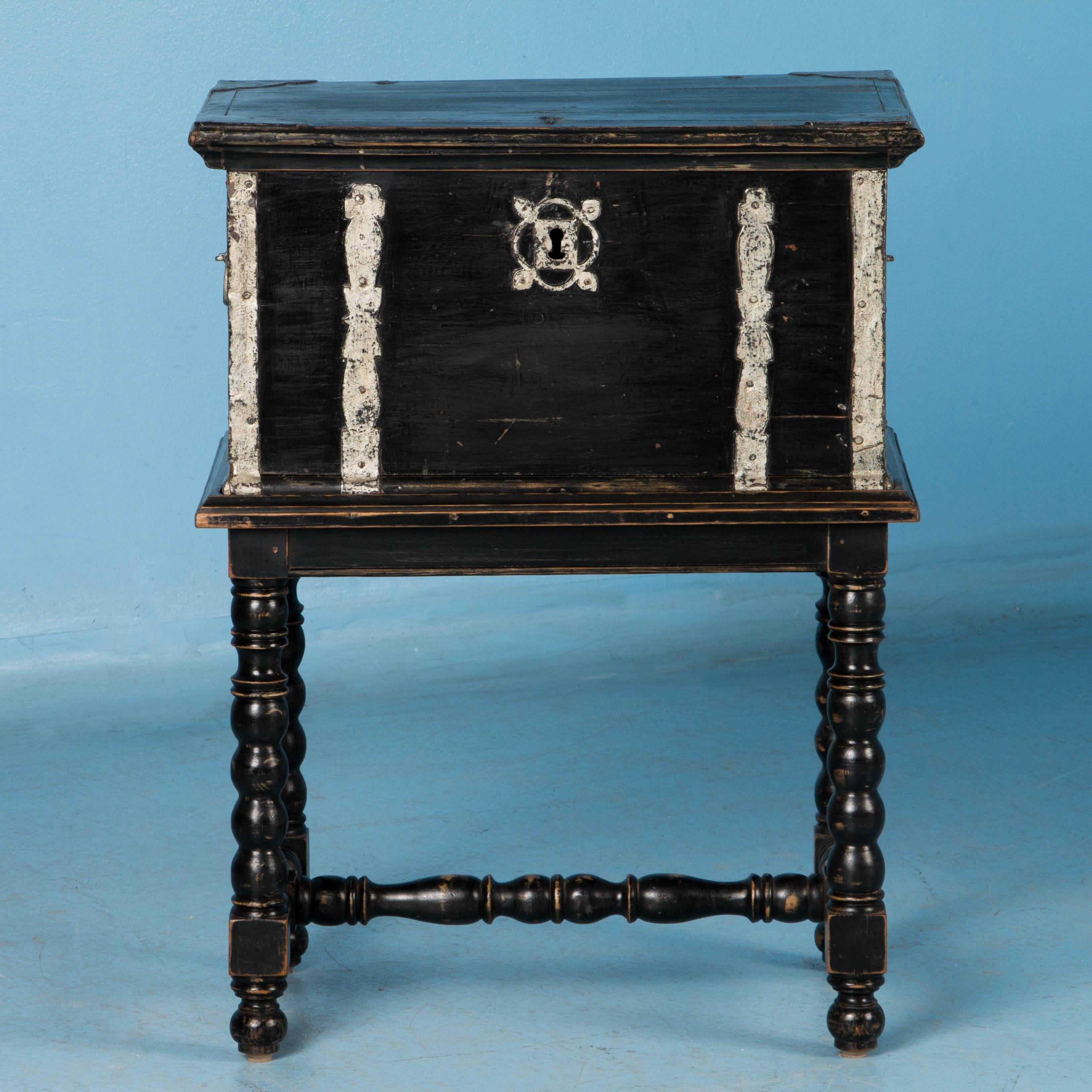 There is a tremendous amount of character packed into a small space in this unique side table. The painted black trunk has wonderful hand-wrought iron work that was painted in an accent color of silver. Boxes reinforced with this type of iron straps