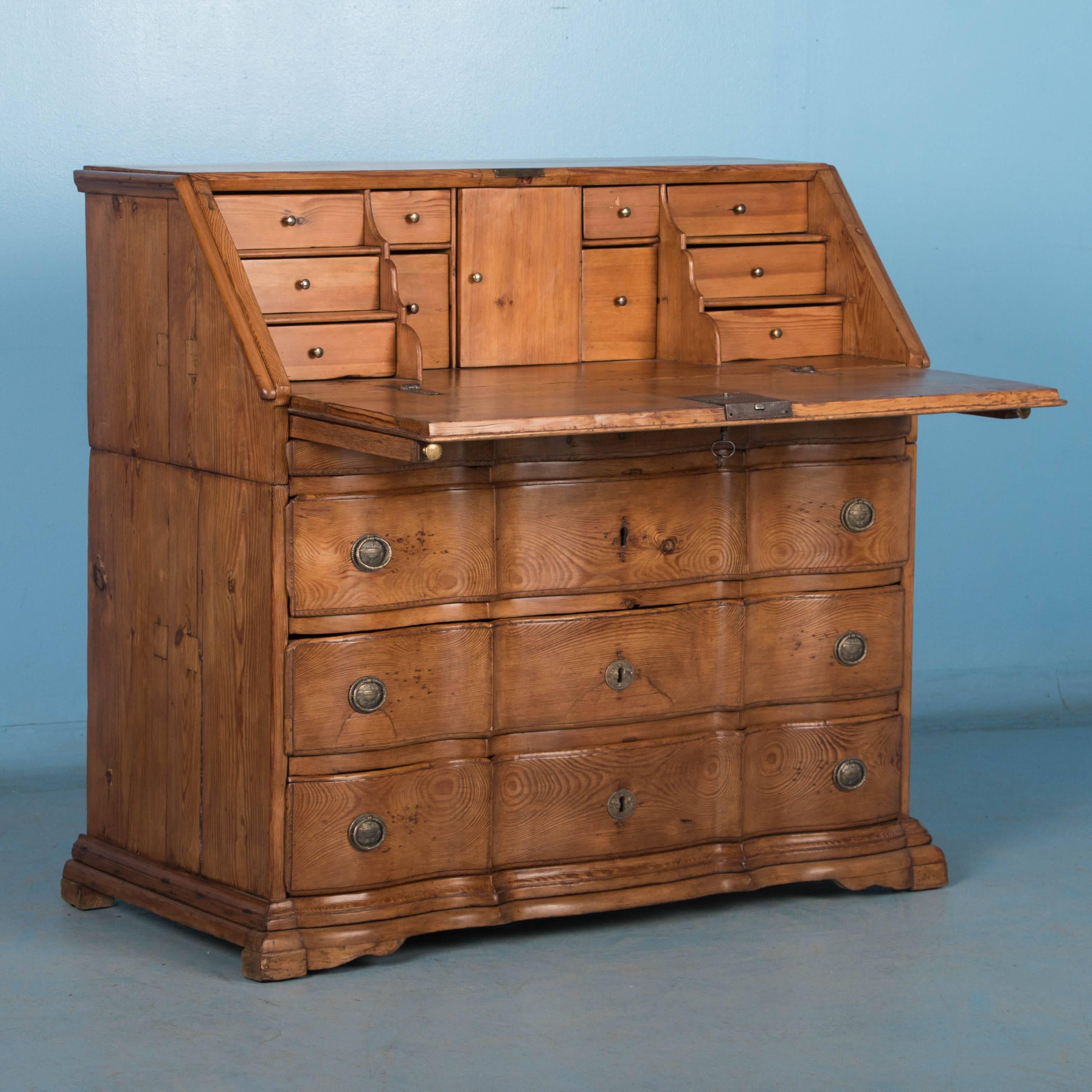It is the deep, rich patina of the aged pine that first captures your attention in this stunning secretary, also known as a bureau, from the late 18th century.  The curved large 3 lower drawers reflect the Baroque period, while the 10 petite drawers