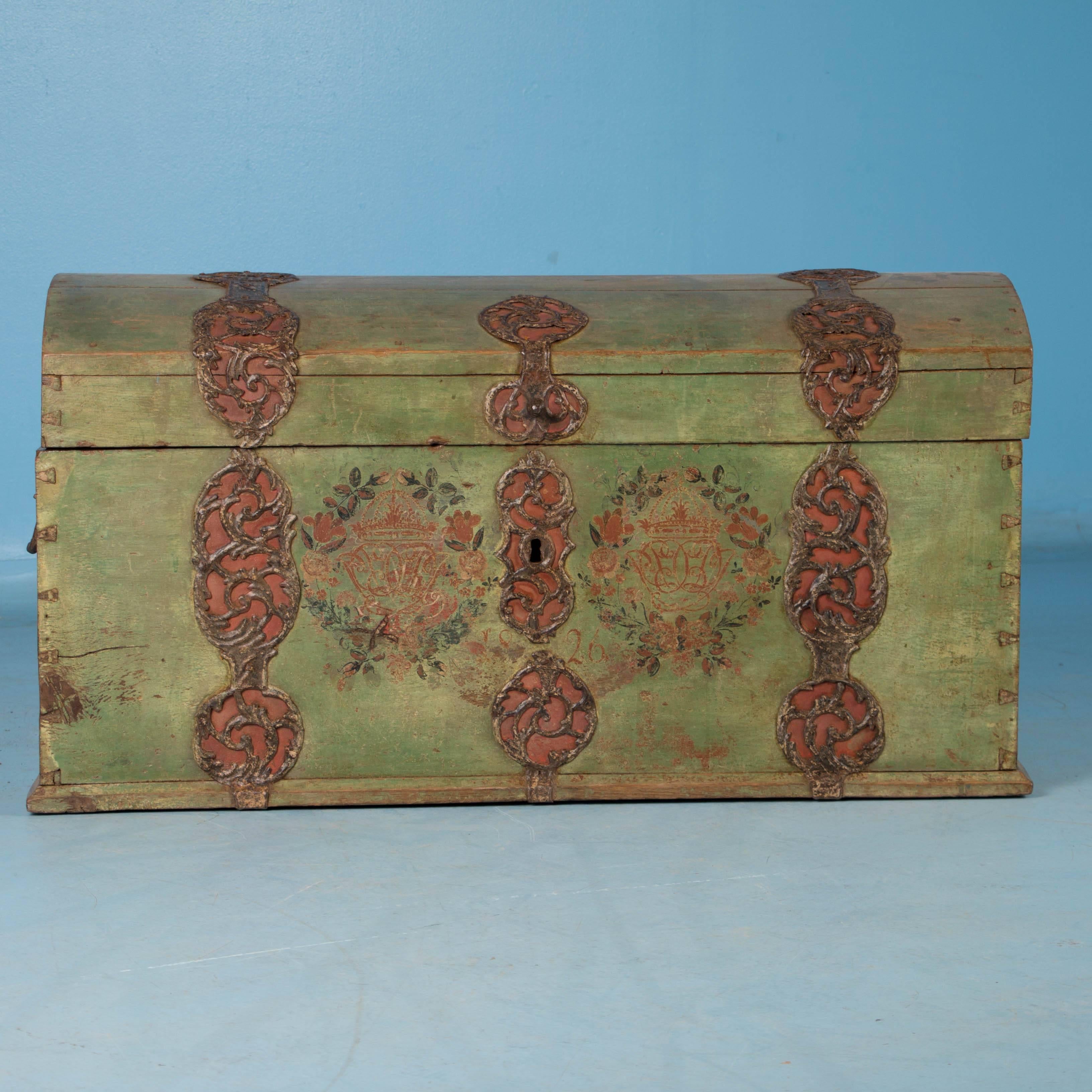 The trunk is dated 1826 below a painted flourish of floral wreaths and monograms over the original time worn green background. The ornate decorative strap and hinges seem to encircle the trunk and set this chest apart from others. Made of heavy oak
