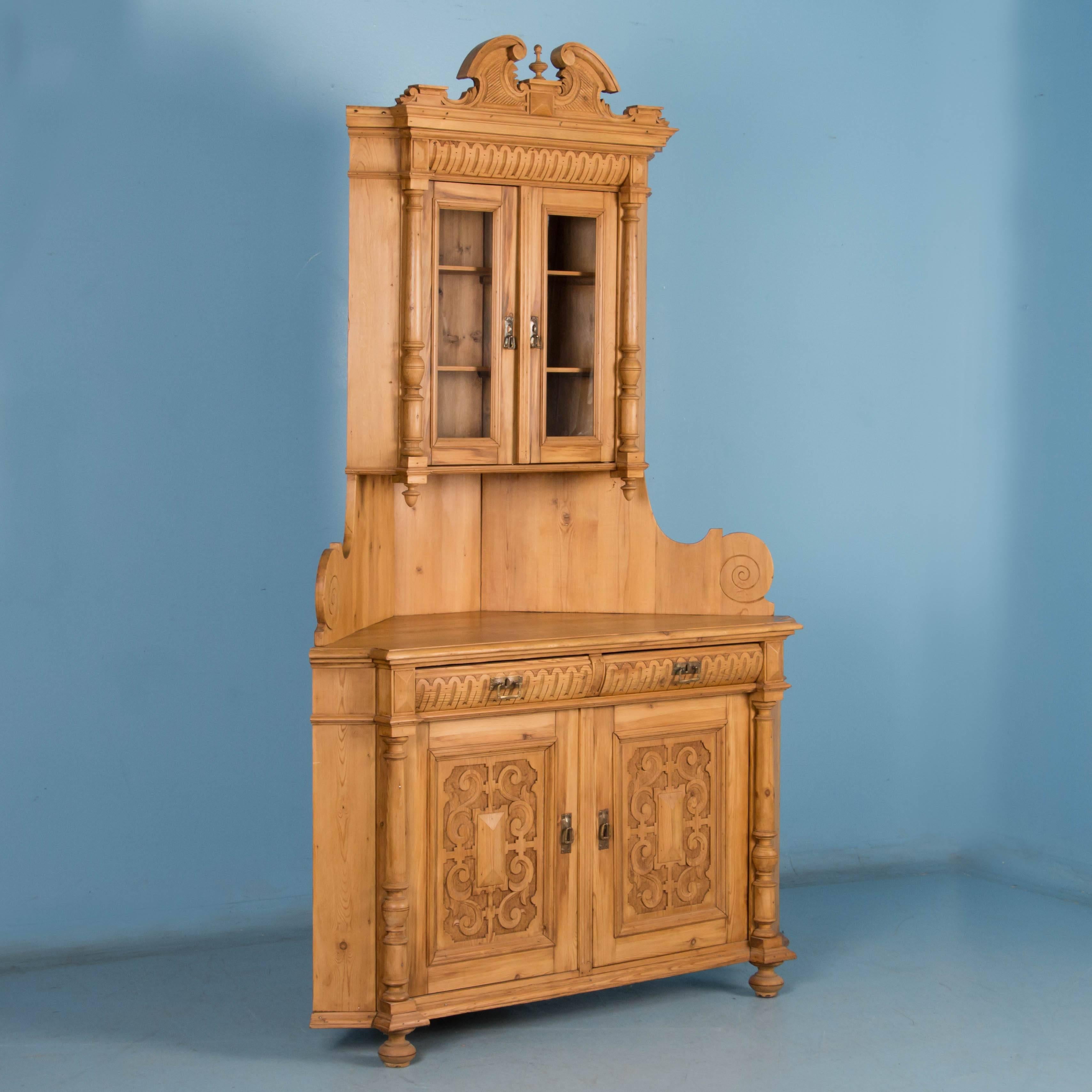 The ornate carving on the panel doors makes a strong statement while the column details, finials, and crown add an ornate touch to this original pine corner cabinet. Please examine the photos to appreciate how all these features blend together for a