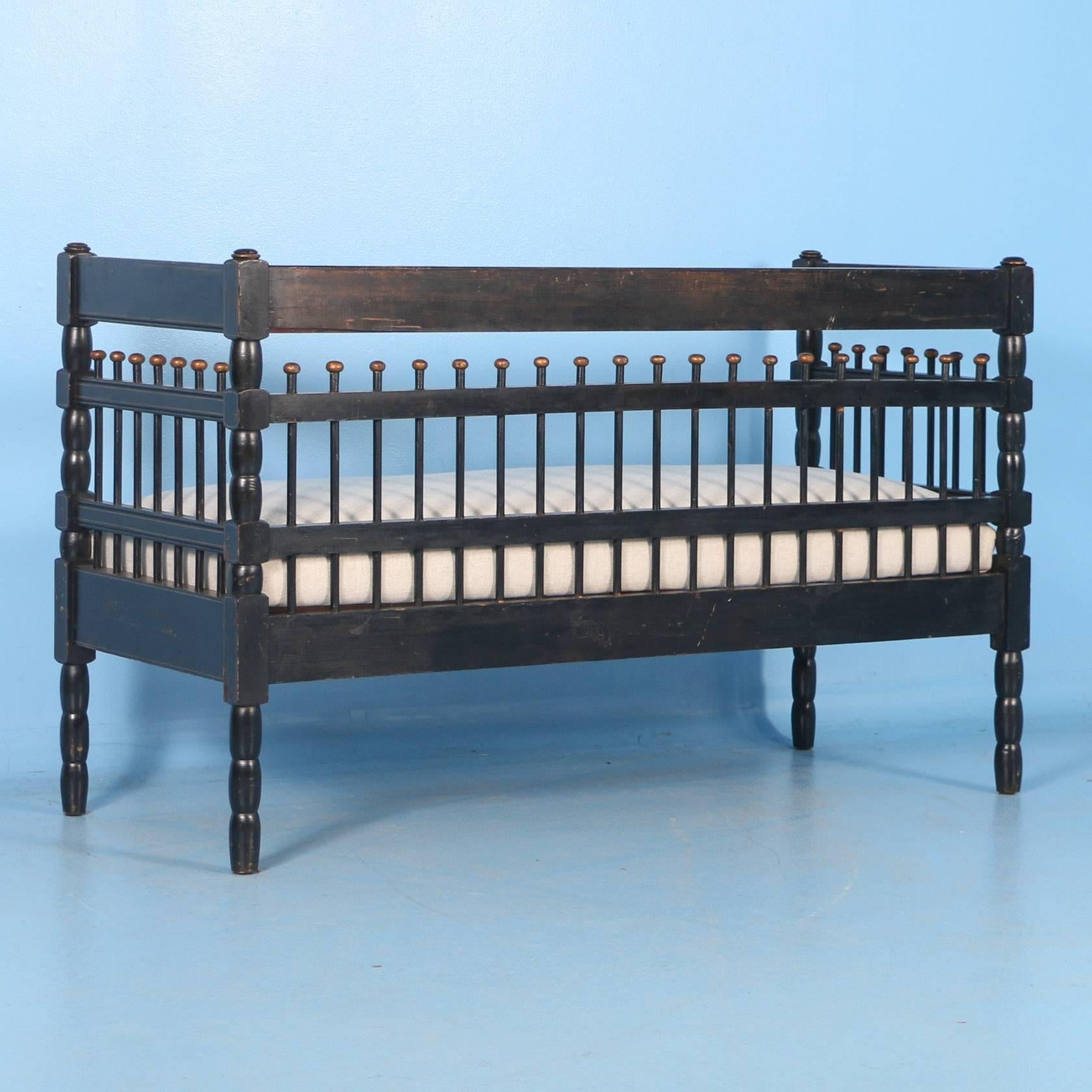 The paint is all original on this black bench with gold trim from Sweden. It was made in the Gustavian Style and has an attractive spindle back. The unusual smaller size allows it to be placed in a wide variety of spaces. The seat was recently