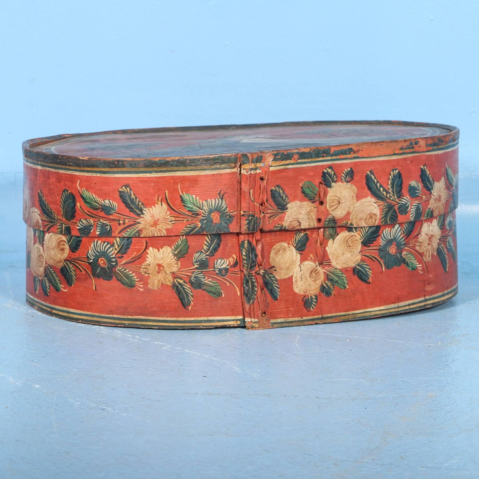 This delightful wooden container or wooden box with lid still maintains the lovely  original folk art paint of a charming couple standing between trees. The man is wearing a top hat, dress coat and walking stick while the lady on his arm has a