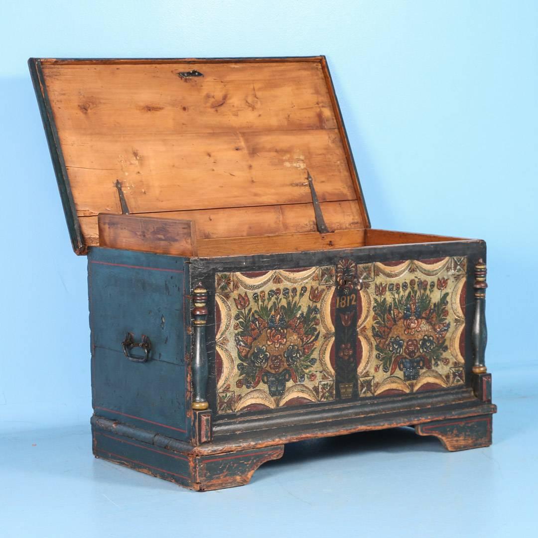 This lovely trunk still maintains its original dark blue, red, white and green paint, including elaborate floral details along the front panels. It has decorative half column details, and hand-wrought iron handles and interior hinges. Please examine