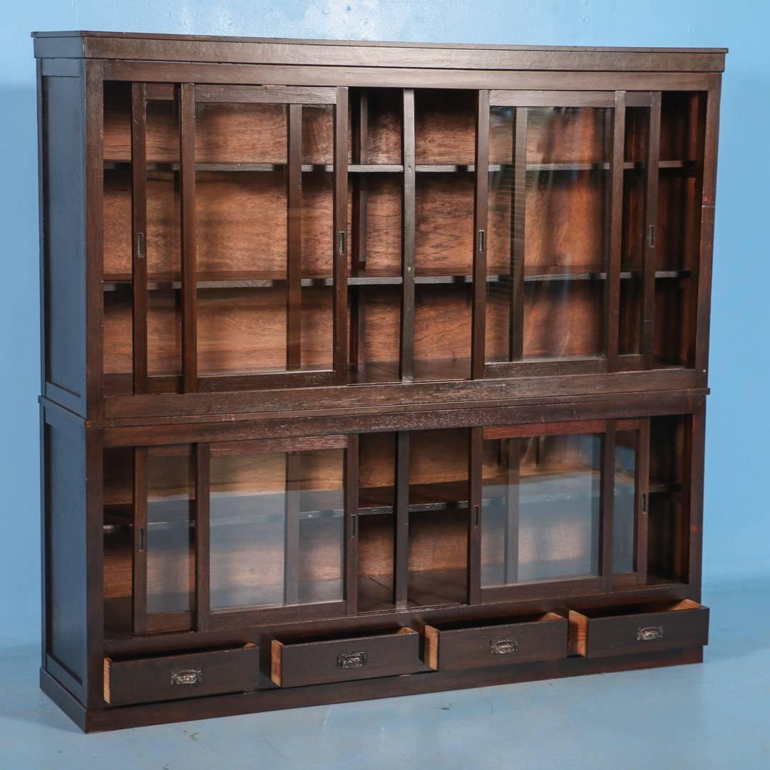 This beautiful antique Japanese bookcase has 8 sliding glass doors with shelves inside and four drawers near the base. The multiple sliding doors make it highly versatile as both a bookcase or excellent display cabinet. The entire piece has been
