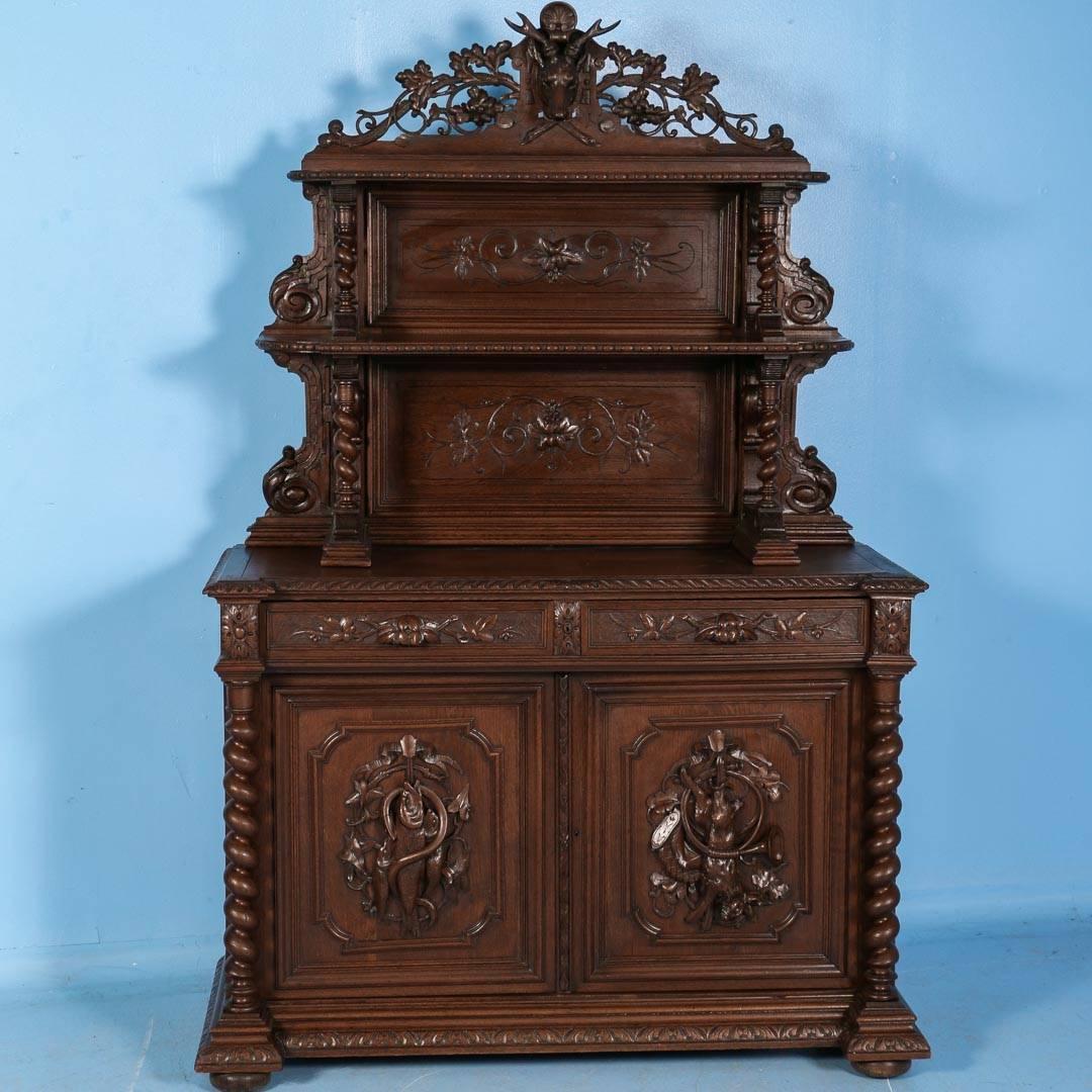 Beautifully crafted oak hunt cabinet from southern Germany reminiscent of the Black Forest carvings of the region. The cabinet was made in two pieces, the top consisting of two shelves supported by twisted columns, carved panels and topped with a