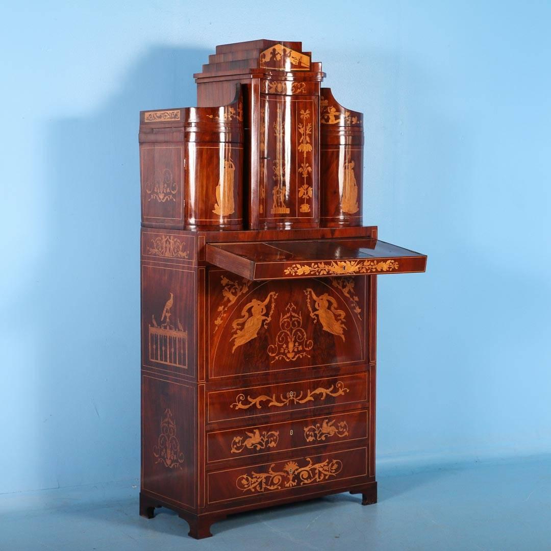 Extraordinary antique Empire secretary desk circa 1810-1820 from Denmark or N. Germany. The cabinet is made in three sections and covered in mahogany veneer with lighter inlays. Behind the drop front, the interior is fitted with a number of smaller