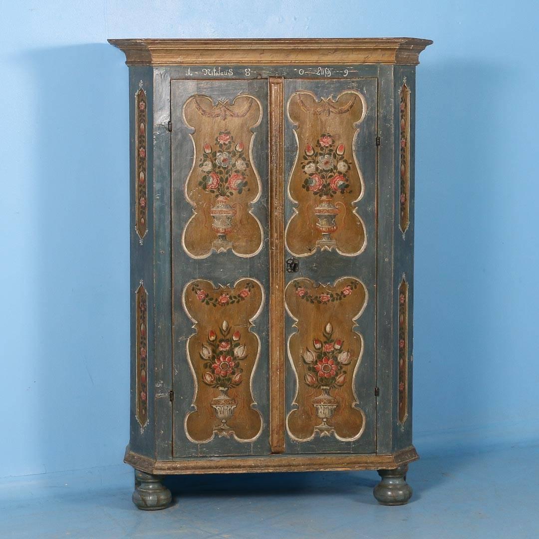 Incredible antique two-door armoire original soft blue/grey from Hungary and dated 1809. Each door has two beveled recessed panels painted olive green with painted floral vases in exceptional detail. The beveled front edge is also paneled with a