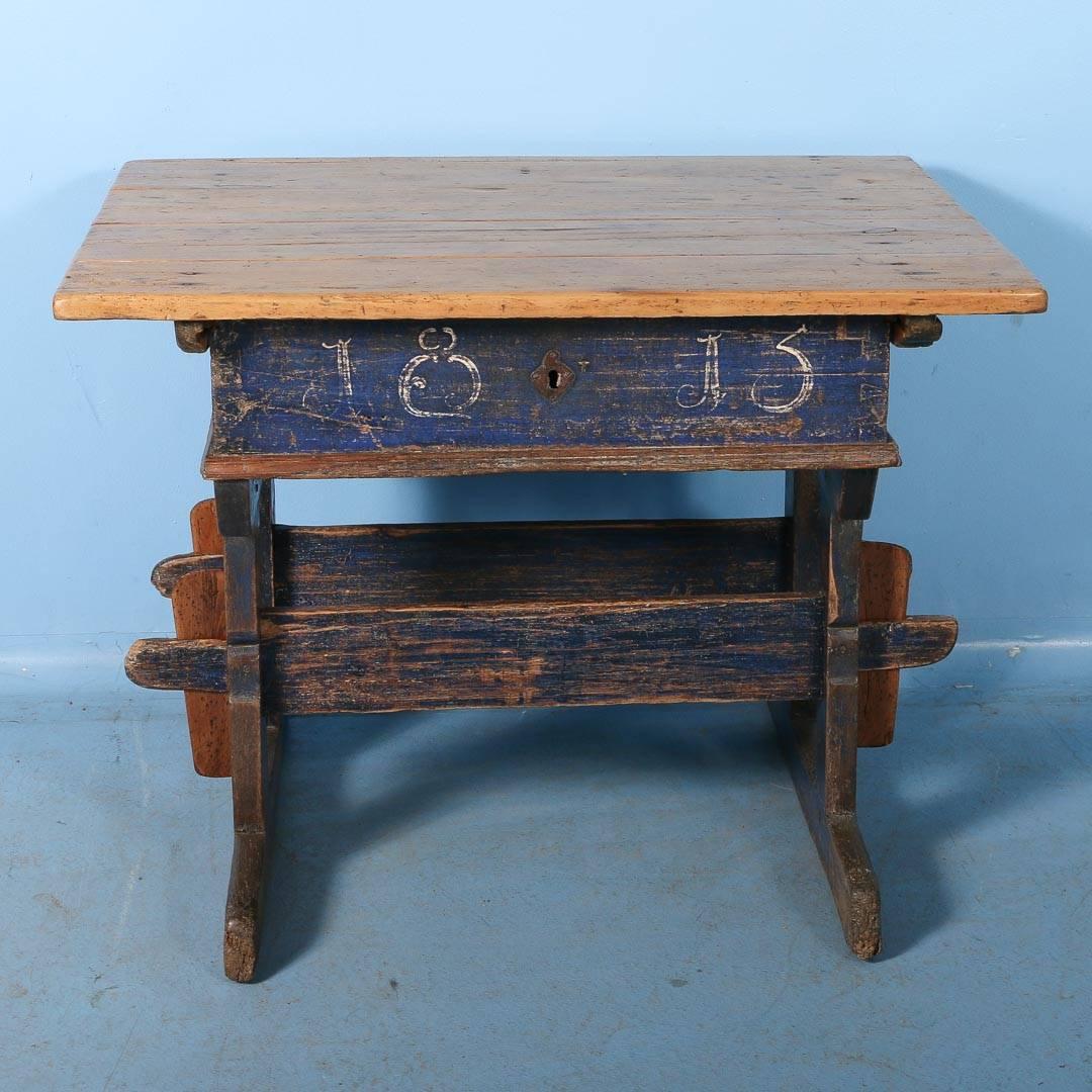 This is a unique and wonderful find! This pine Hungarian baker's table with the original blue paint is dated 1813. The natural pine table top slides in either direction, to expose a large storage space. The paint is worn in places showing the