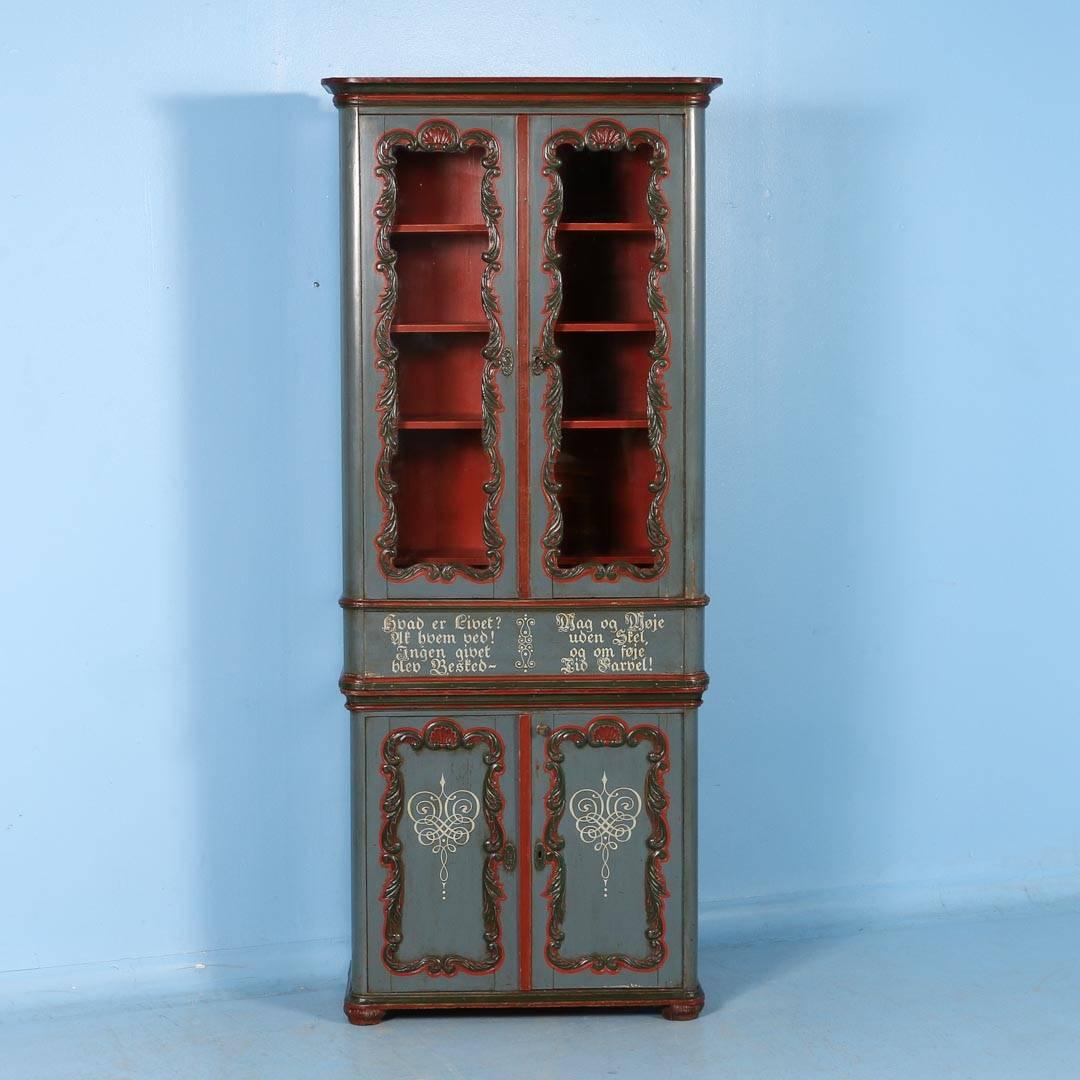 This antique carved and painted display cabinet from Denmark is made in 2 parts. The upper section has 4 shelves behind 2 glass doors and the bottom has 2 carved and painted paneled doors with 2 shelves inside. Retaining it's original paint, the