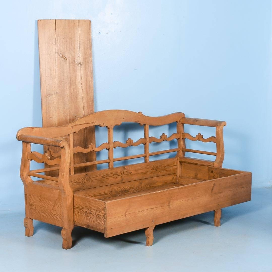 This lovely pine bench is a wonderful example of Swedish country craftsmanship in the Karl Johan design and period. The gentle curve of the arms and lovely carved details add to its allure. The seat opens to reveal storage space below. Note in the