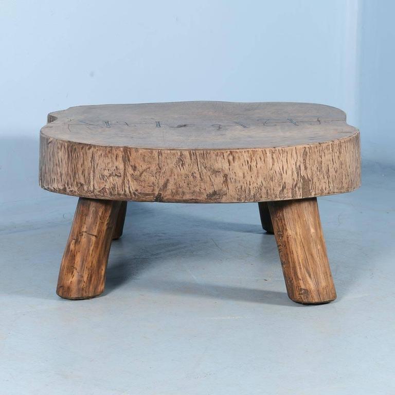 A rustic oval coffee table made from a single thick slab of wood. The slab is between 7
