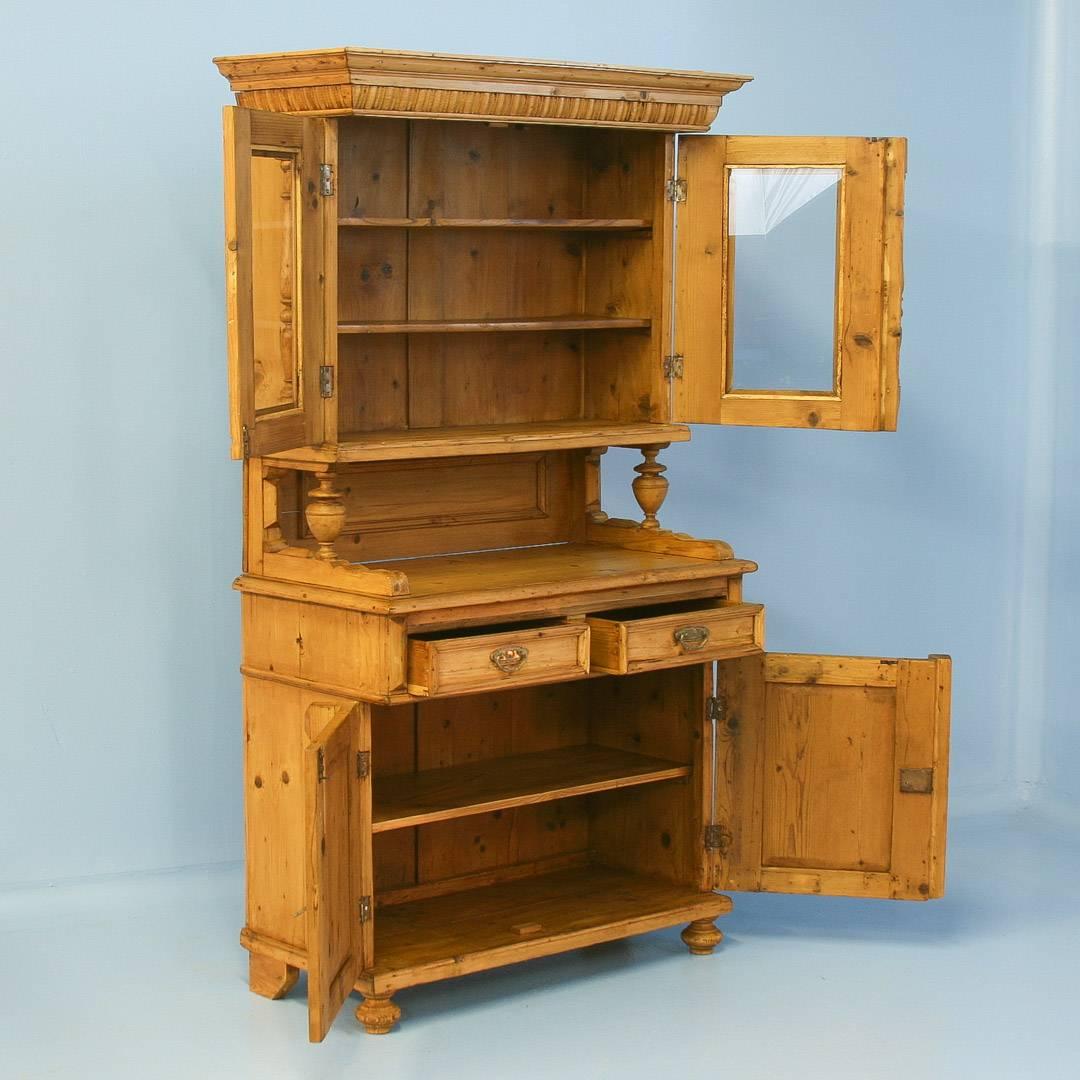 This pine cupboard has decorative elements that make it special, such as the turned column accents and carved crown molding details along the top. This cupboard likely displayed the household china and serving ware in the 1800’s. The top section is