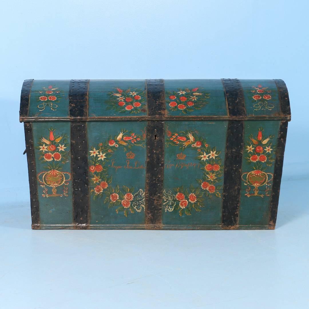 An exceptional antique Swedish dome top trunk with original paint, dated 1847. The rich blue green background provides the perfect contrast for the red and white floral details. Inside the center garland is the name Ingar Jons Dottir and the date of