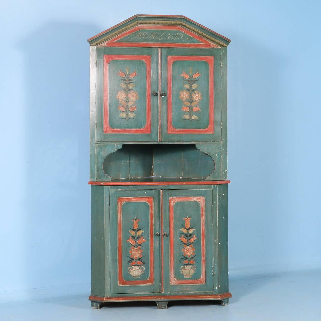 This antique pine corner cabinet from the mid-1800s, original soft green and floral painted details, is made in two parts creating an open niche between the upper and lower cabinets. Both the upper and lower section are painted a light salmon color