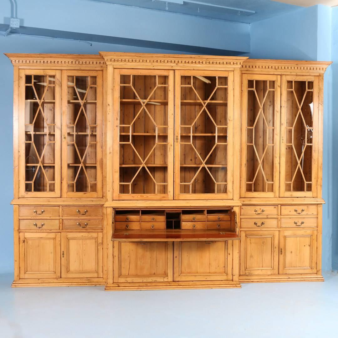 This remarkable large pine breakfront bookcase is from England, circa 1890. It is built in six sections (three upper and three lower) to facilitate easier transportation and installation. The upper glass doors have lovely accent trim adding to the