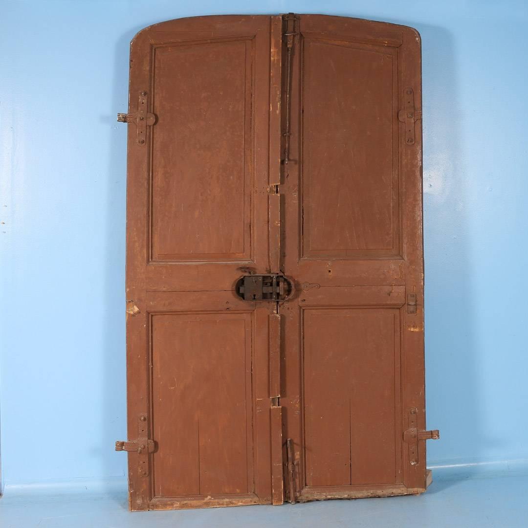Pair of large antique French pine entry doors, circa 1820-1840 painted a dark rust color. Sold as is. Doors are physically solid/strong. Please examine photos for condition and rustic finish.

Scandinavian antiques imports containers from Europe
