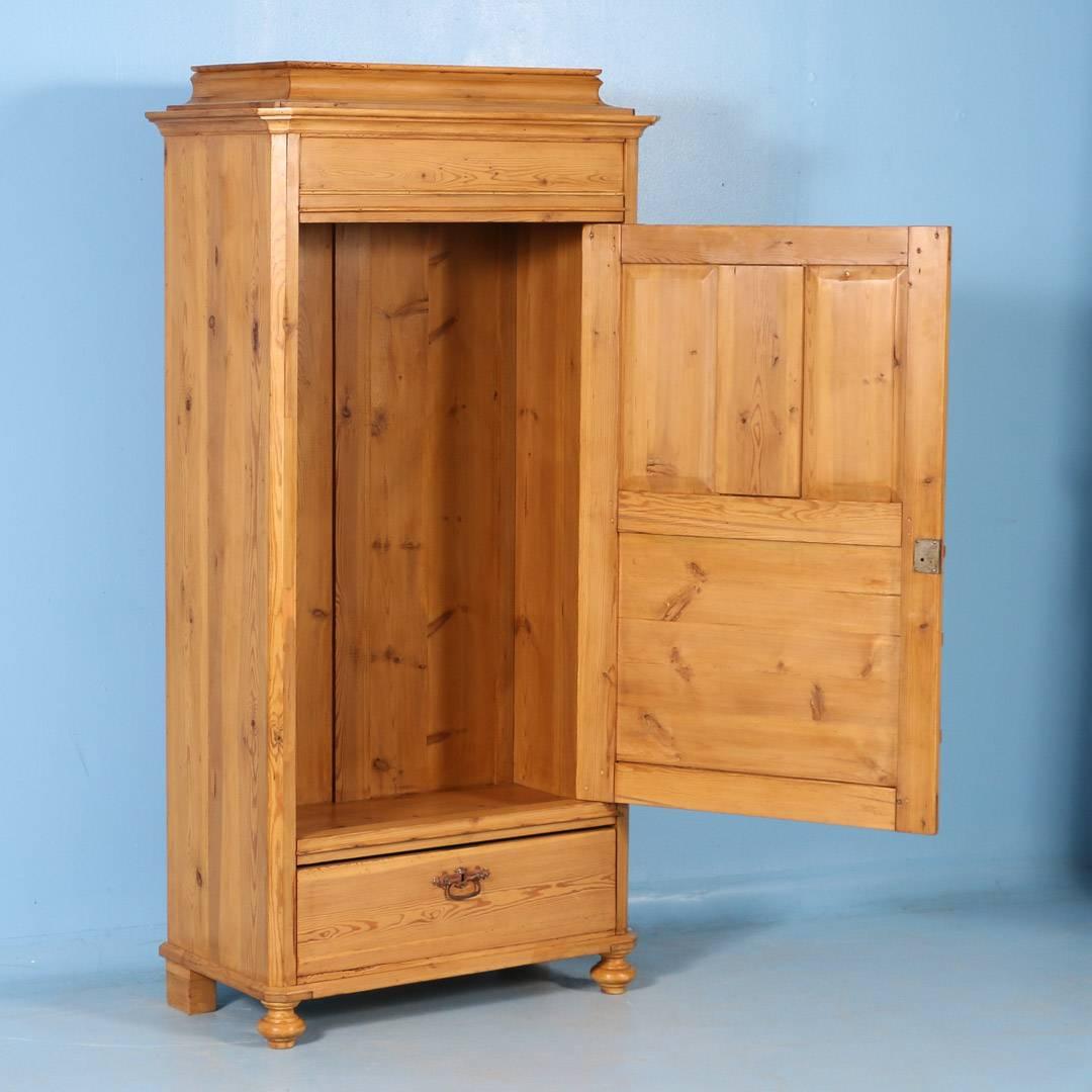 This Danish pine single door armoire is sometimes referred to as a 'false front' as it was designed to look like a two-door cabinet with drawers underneath. The reality is that this is just an 