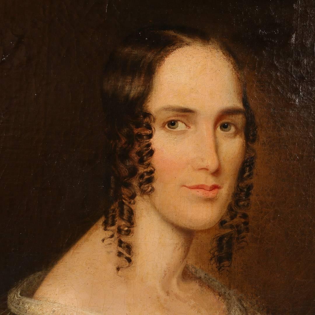 Large unsigned early 19th century oil painting portrait of a seated woman, American circa 1800-1820.  In a formal dress with white lace collar her expression is almost detached, yet she still has an air of elegance and grace. The canvas is unsigned