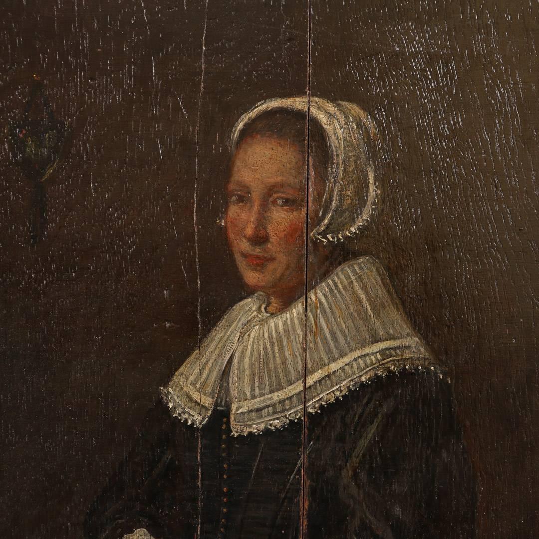 Unsigned antique Dutch painting of a young woman of the 17th century, painted on an oakwood panel, circa 1840. The two oak panels have separated in the middle of the portrait and an old repair is visible. This is a 19th century copy of Frans Hal’s