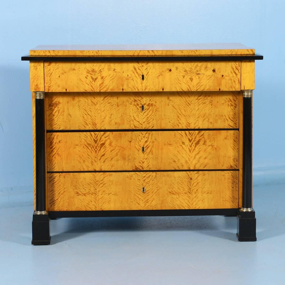 Antique Biedermeier chest of drawers from Sweden, circa 1830. Made of pine and covered in a vibrant birch veneer, this chest features contrasting black molding, block feet and a pair of pillars with brass capitals flanking the three lower drawers.