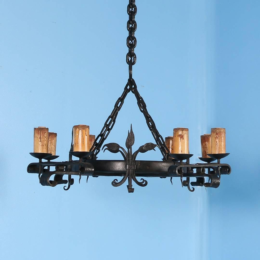 Large antique wrought iron chandelier from Denmark, circa 1910 with a large central chain connecting the four smaller support chains. Four arms radiate out from the center ring each with a pair of lights. Each of the eight sockets are covered with a
