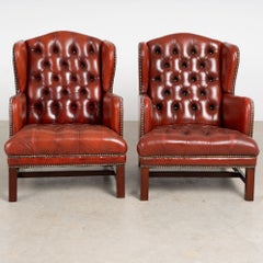 Par de sillones Chesterfield daneses del siglo XX con respaldo de alas, tapizados en piel de color rojo oscuro