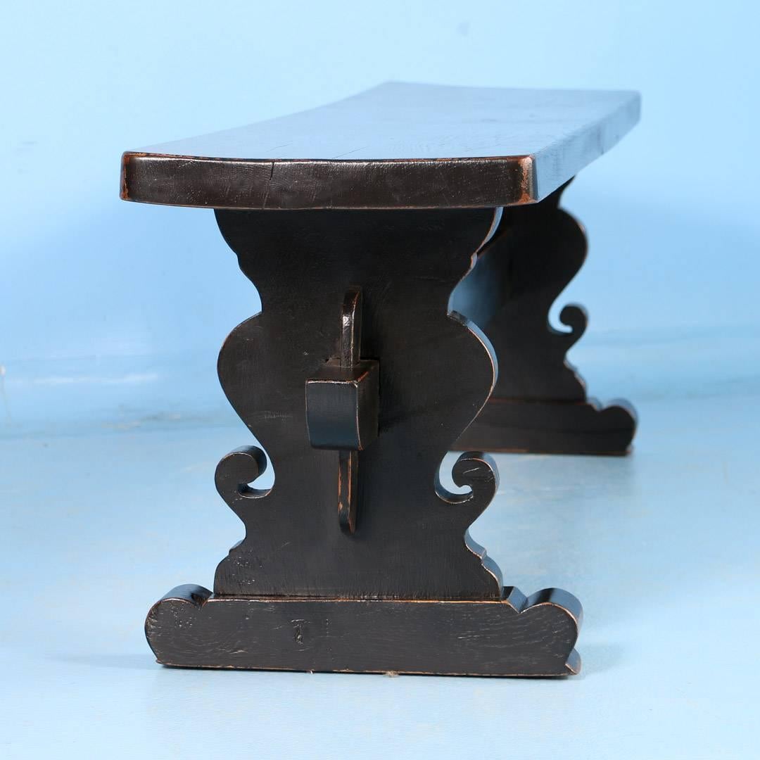 Antique Danish oak bench painted black, circa 1900. Recently painted, the black paint has been worn away to show the natural oak underneath. The bench is sturdy and ready for use. Note the wonderful carving of the trestle base in close up