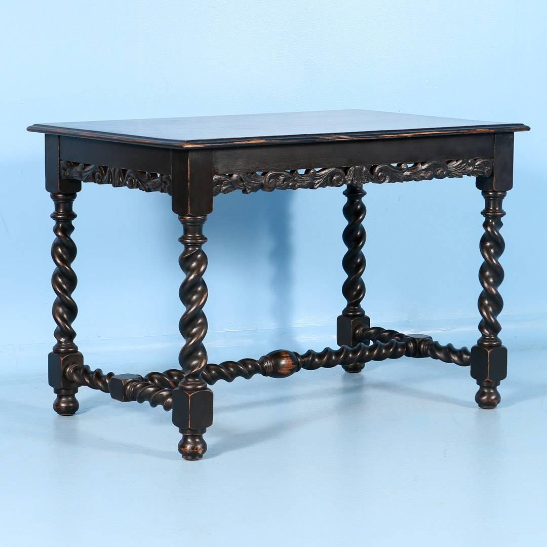 Antique oak Renaissance Revival writing table from Denmark, circa 1890. Below, a turned stretcher connects the four twist legs which support the tabletop and carved aprons on four sides. Recently painted, the black paint has been worn away to show