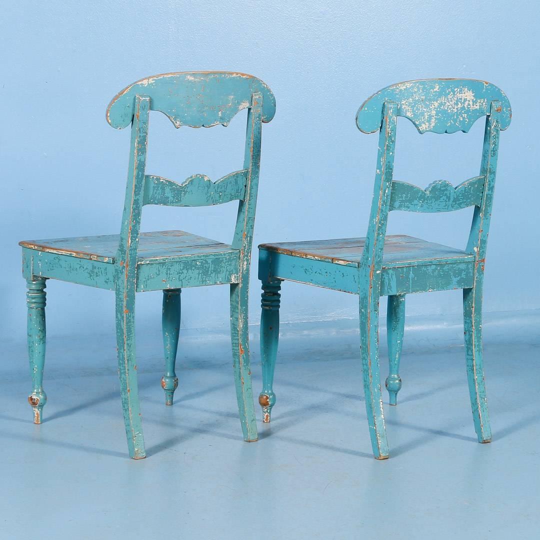 An antique pair of side chairs from Sweden, circa 1860, with original blue paint. The scrolled back and single carved back splat are a traditional Swedish design. Under the blue paint are remnants of a darker blue and cream colored paint giving the