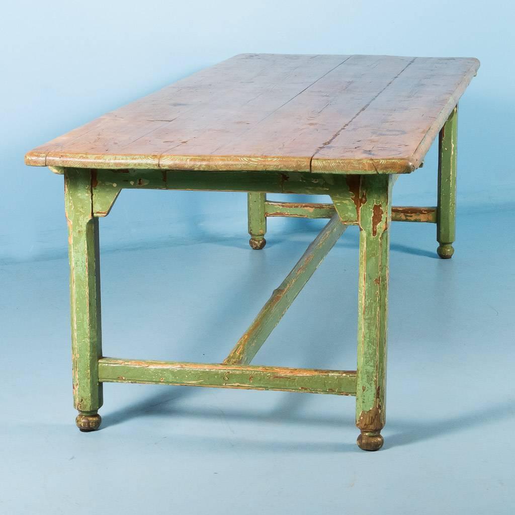 Large pine harvest table from Sweden, circa 1840-1860. The original four plank top, beautifully worn over time with the expected scrapes, scratches and dents is a natural pine with remnants of the old green paint found on the base. The painted table