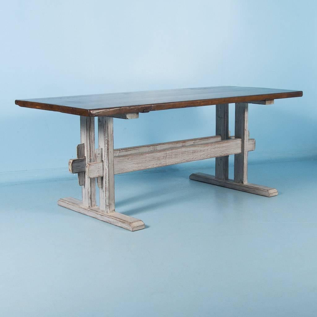 Antique farm table from Denmark, with a hardwood top and a trestle base with distressed gray paint. The four plank top has been sealed with a durable finish making it strong and easy to clean. The double stretcher and wide platform feet of the base