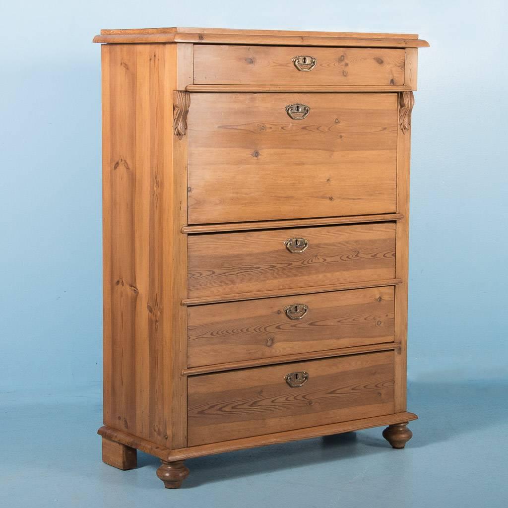 Antique pine drop front secretary desk from Sweden, circa 1860. The desk has four large drawers with brass pulls, one above the desk opening and three below. The desk interior is fitted with a number of small drawers, each with matching brass knobs