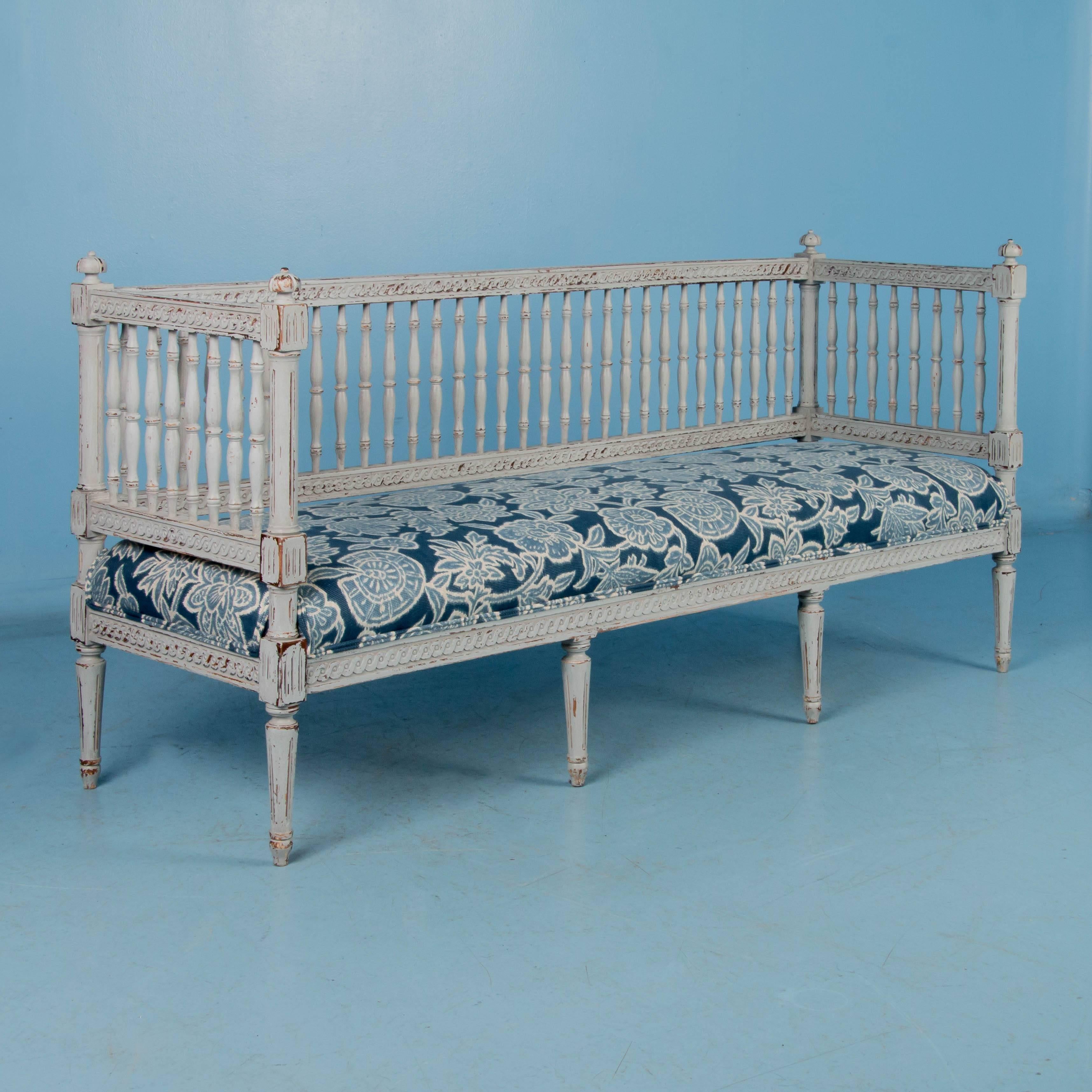 Mid-19th century antique sofa or bench with spindled back and sides, resting on eight tapered feet, painted in the exquisite colors of the Gustavian period. Where the light gray painted finish is worn away, the darker natural wood comes through,