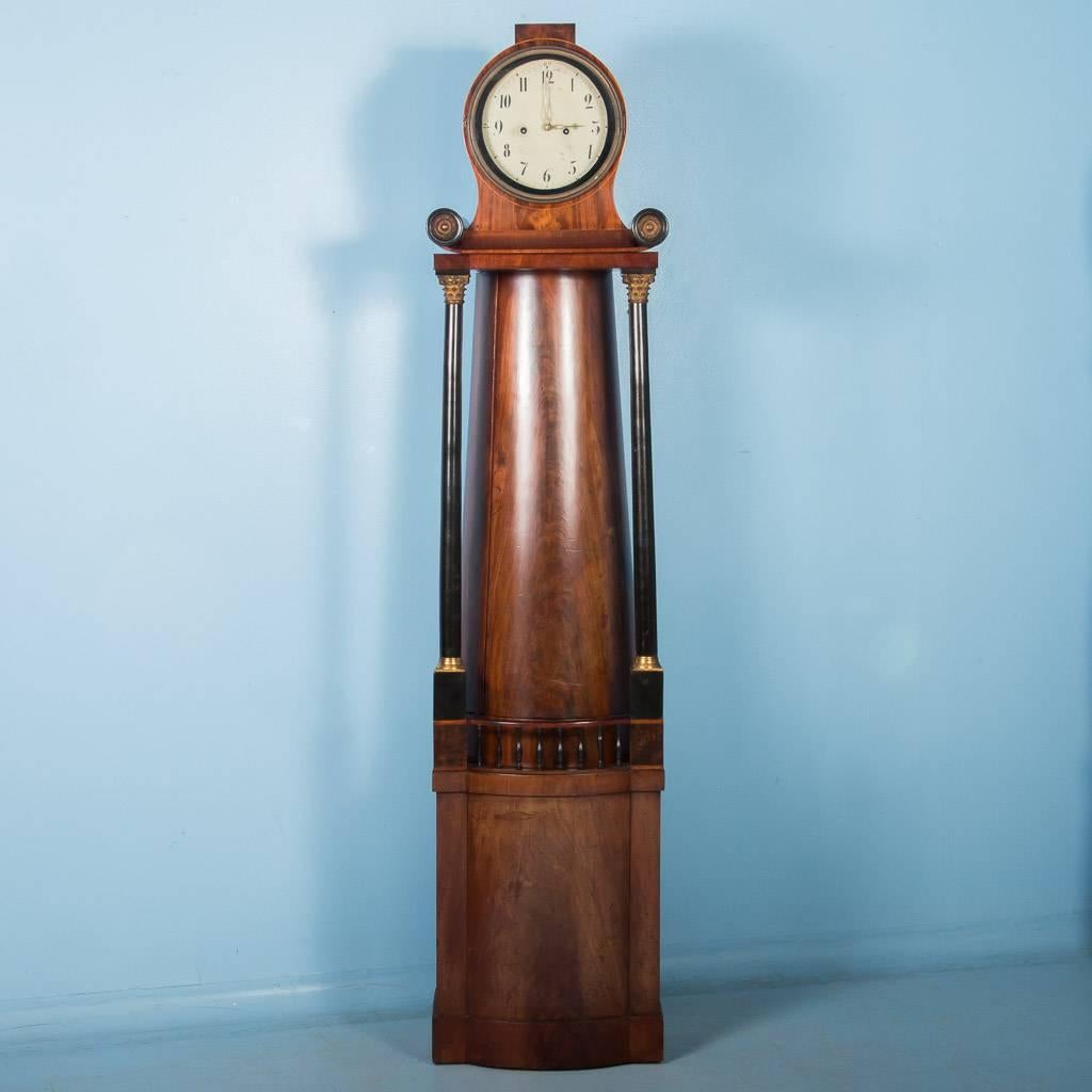 Exceptional antique Biedermeier grandfather clock from Germany, circa 1830. A pair of ebonized pillars with brass Corinthian capitals anchor the base with the upper casework and add a perfect contrast to the flame mahogany case. Please enlarge the