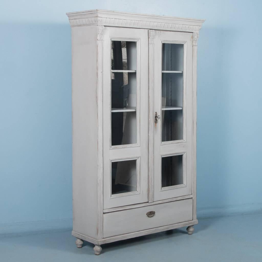 Pair of matching antique glass front bookcases from Sweden painted gray, circa 1860-1880. Both cabinets features two locking hinged doors with glass panels, three adjustable shelves and a single working drawer below. On each piece the gray paint has