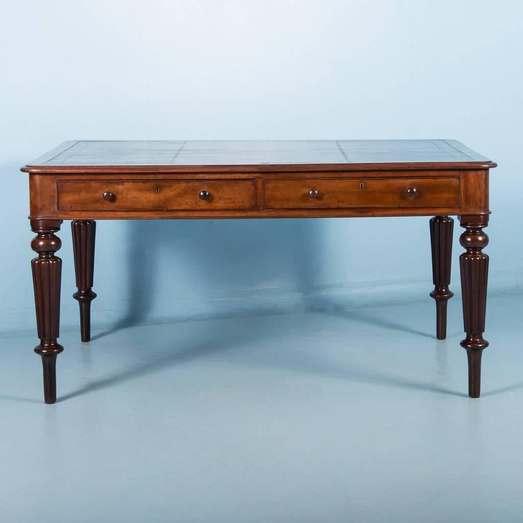 Antique mahogany writing desk from England, circa 1840-1860, with an embossed leather top. The apron has two working drawers on one side and two false front drawers on the opposite. The desk is very sturdy and beautifully finished, with it’s