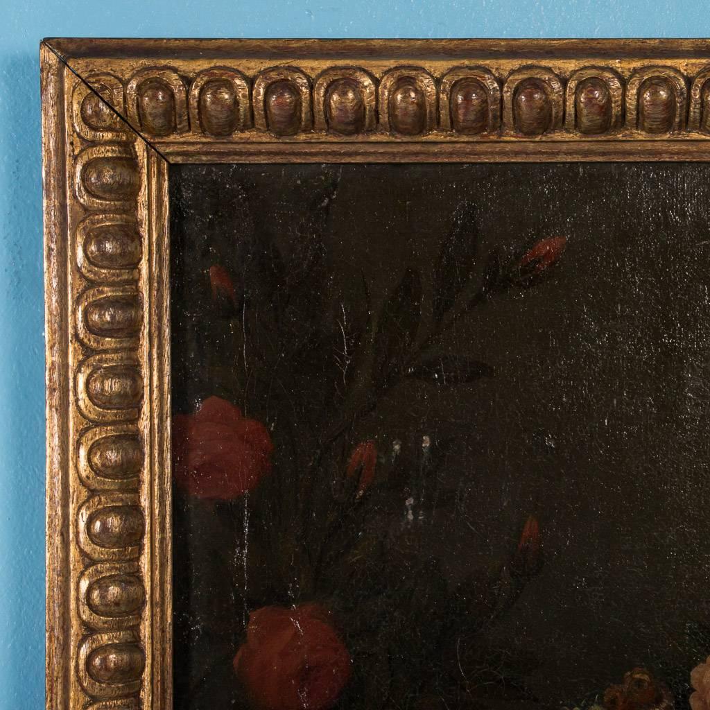 Original antique oil on canvas painting, portrait of a young woman, circa 1820-1840. Surrounded by red rose bushes and sitting on a bench, the elegant young woman appears to be weaving a garland of flowers while leaning on a stone railing. Her