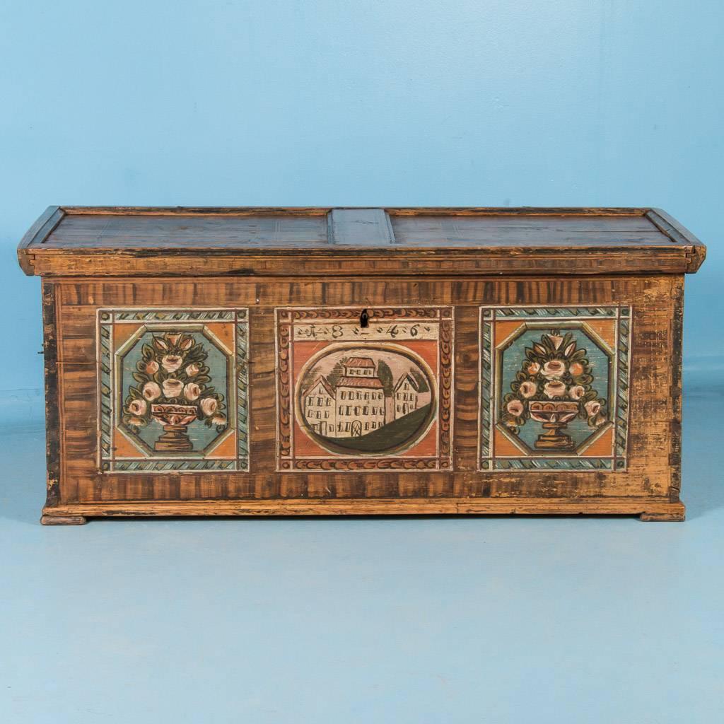 Antique 19th century painted pine trunk from Austria, dated 1846. Most of the original painted design remains on the top, both sides and the front, which features 3 square panels. The center panel has the date of 1846 painted above the red roofed