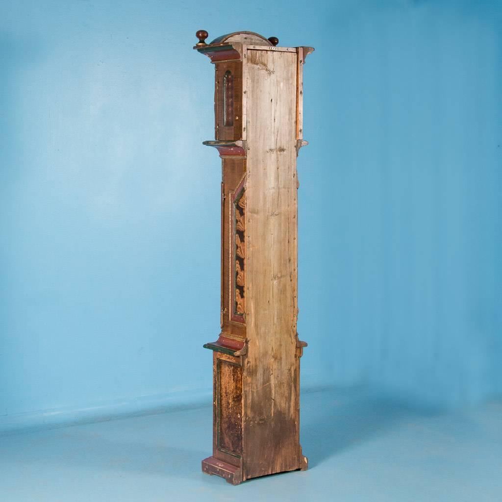 Antique Danish grandfather clock with original painted finish, circa 1800-1820. The front and side panels are painted in earth tones, imitating burled wood and stylized plants. The molding painted in red, gold and green, compliments the Danish