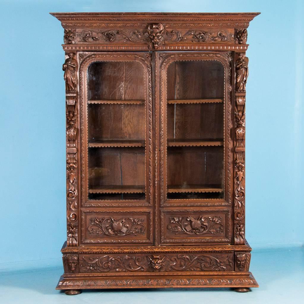 Exceptional hand-carved American Renaissance Revival oak bookcase, circa 1870. Every part of this extraordinary cabinet is carved. Most notable are the two robed figures, over 13