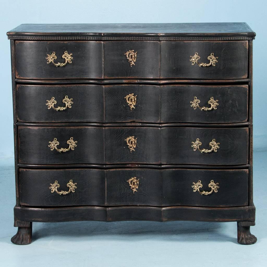 Antique baroque chest of drawers from Denmark, circa 1750-1800. The black painted finish has been lightly scraped and sanded exposing the natural elmwood beneath and highlighting the details of the casework. The scalloped contours of the top are
