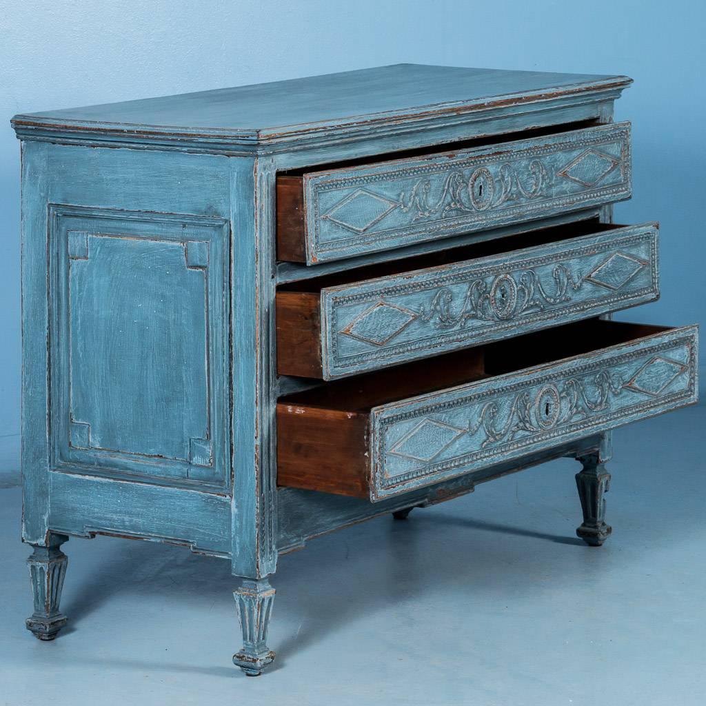 Carved late 18th century antique French Louis XVI oak chest of drawers, circa 1800-1820, with blue paint. The warm, lightly distressed blue paint, with flecks of light blue and white, exposes the darker oak beneath and highlights the carved details