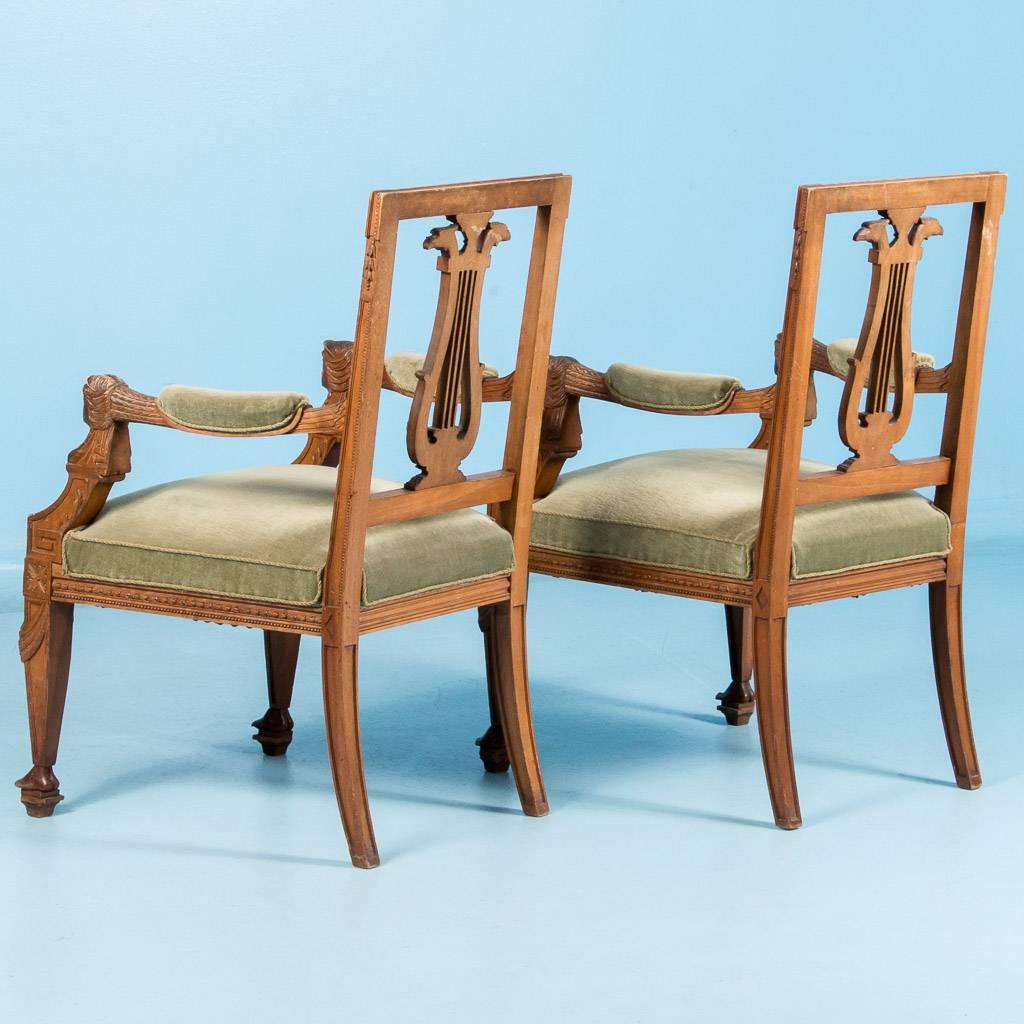 Pair of carved antique French neoclassical armchairs, circa 1840-1860. This exceptionally well carved pair of arm chairs features a lyre back splat topped by a pair of eagle heads, and connecting the arm with the arm support are a pair of female