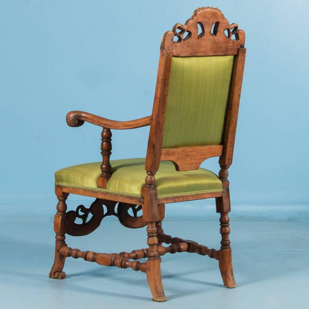 Carved antique 19th century upholstered armchair from Norway, circa 1850-1870. The back and seat are upholstered and covered in a green satin fabric which complements the dark natural hardwood of the frame. The back legs, arm supports and stretchers