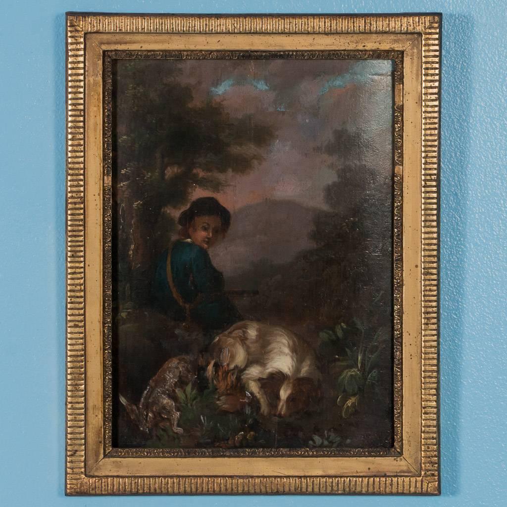 Pair of small original French 19th century oil paintings of hunting scenes, circa 1800. The pair are both painted on wood panels, each depicting a woodland scene with a young man, his dog and the small game from the day's hunt. Both are mounted in