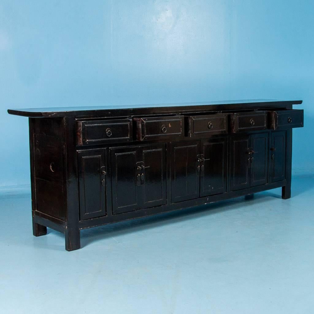 Large antique black lacquered buffet or server from China, circa 1880. There are five pegged and dovetailed drawers above a series of three double and two single doors, with ample storage inside. All the drawers and doors are fitted with bronze