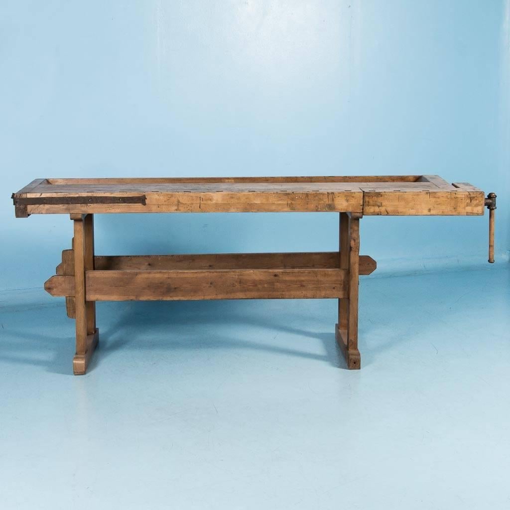 Antique 19th century, Danish carpenter's workbench, circa 1920. This workbench has a single vice with a wood handle and a recessed tray where the carpenter would lay his tools and for catching debris. The traditional keyed trestle base allows it to