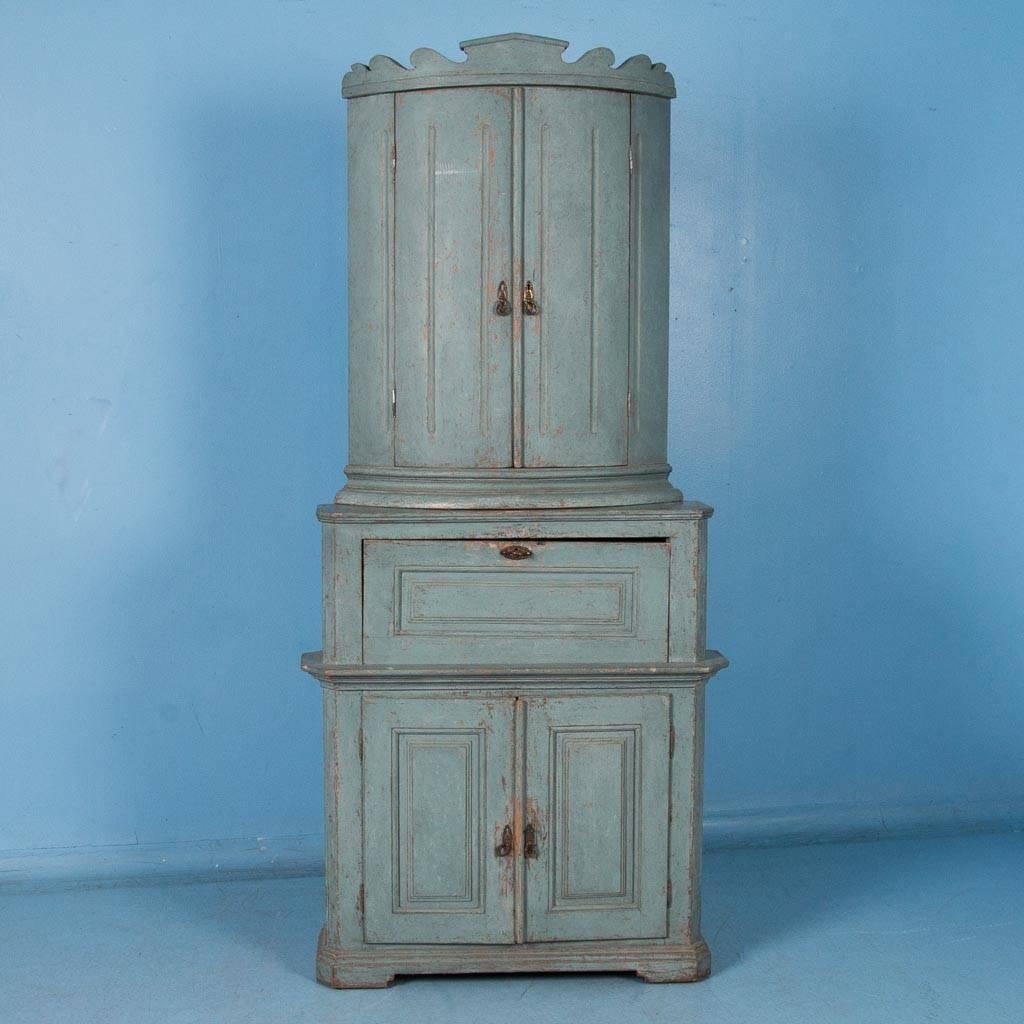 An exceptional Gustavian pine corner cabinet from Sweden with slightly distressed original soft blue paint, circa 1810-1830. Made in two sections, the upper cabinet with it's bowed doors rests on the squared lower section which has an unusual drop